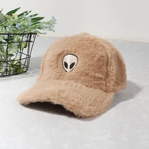 Detailed view of brown plush baseball cap with alien embroidery and soft furry texture