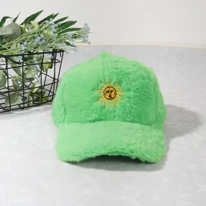 Détail de la casquette de baseball en peluche vert vif avec broderie soleil jaune et texture