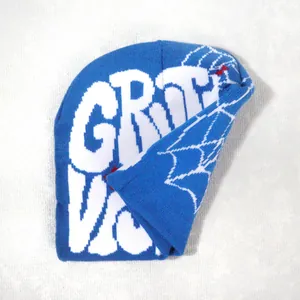 Close-up of blue knitted beanie with white GROOVY text and spider web pattern detail