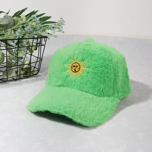 Gros plan sur la casquette en peluche vert fluo avec broderie de soleil jaune détaillée