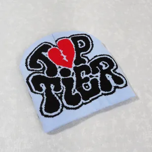 Close-up of light blue Y2K beanie with Top Tier lettering and a red broken heart graphic