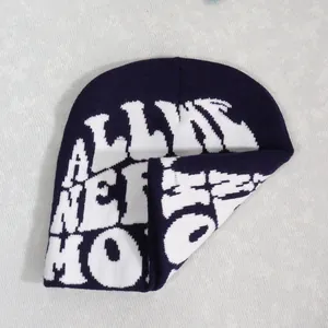 Close-up of knit beanie showing white jacquard alphabet text and dark blue fabric texture