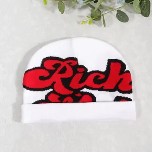 Detail of white knit beanie featuring a bold red graffiti style Rich text embroidery