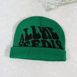Detail of green knitted beanie featuring black text jacquard and ribbed cuff design