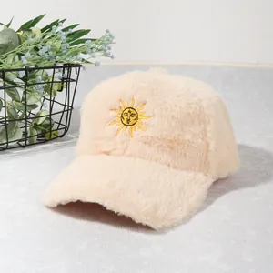 Gros plan d'une casquette de baseball en peluche beige avec broderie soleil douce