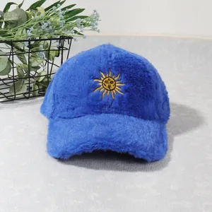 Détail d'une casquette de baseball en peluche bleue avec broderie soleil dorée et visage