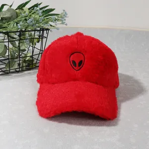 Detailed view of red plush baseball cap featuring a black alien embroidery on soft fabric