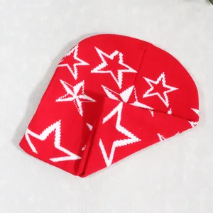 Detalle de un gorro de punto rojo con patrones de estrellas blancas y textura suave