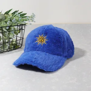 Détail d'une casquette en peluche bleue avec broderie soleil jaune au style hivernal