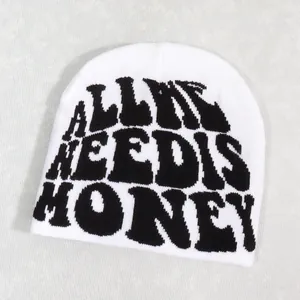 Detailed texture of a white knitted beanie featuring bold black HONEY text on front