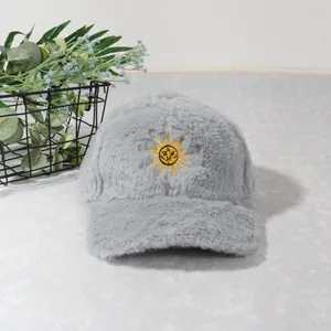 Détail d'une casquette en peluche gris clair avec broderie soleil jaune sur fond doux
