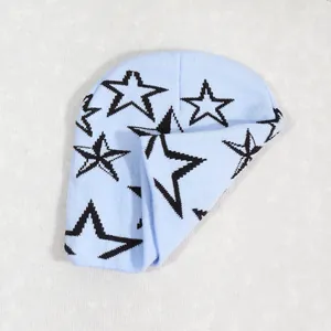 Detalle de gorro de punto azul claro con patrones de estrellas negras en fondo blanco