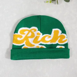 Detail of green knit beanie featuring a yellow Rich letter patch and ribbed turnover cuff