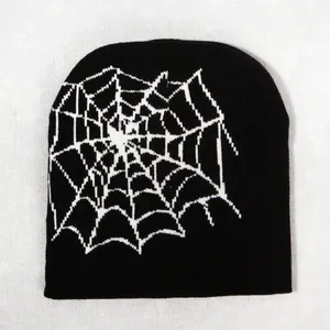 Close-up of black knitted beanie featuring white spider web pattern texture and stitching