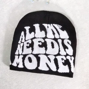 Detailed view of black knitted beanie featuring white 'ALL I NEED IS MONEY' slogan embroidery
