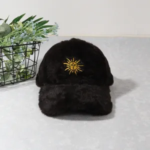 Détail de la casquette de baseball en peluche noire avec broderie soleil dorée et fausse fourrure