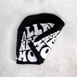 Close-up of black knitted beanie with white jacquard letter pattern and soft texture