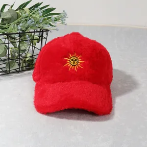 Vue détaillée d'une casquette de baseball rouge en peluche avec broderie soleil jaune et texture