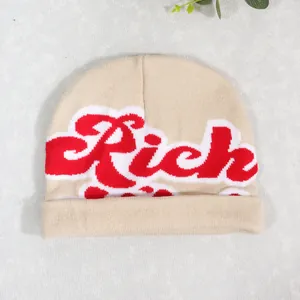 Detailed close-up showing the knit texture and Rich letter embroidery on the beige beanie