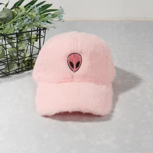 Close-up of pink plush baseball cap with embroidered alien patch and soft faux fur texture