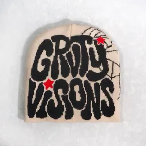 Detailed close-up of knitted cream beanie with black GROOVY VISIONS text and red stars