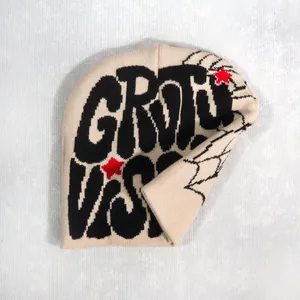 Close-up of cream knit beanie featuring black jacquard letters and red star detail