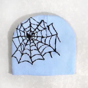 Detail of light blue knit beanie showing black spider web pattern and fabric texture