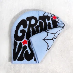 Detail of light blue knit beanie featuring black graffiti letters and spider web patterns