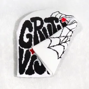 Close-up of white knitted beanie featuring bold black graffiti text and woven texture