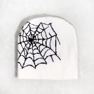 Detail of white knitted beanie featuring a bold black spider web pattern for streetwear
