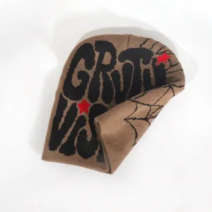 Detailed close-up of khaki knit beanie with black spider web and red star graphics