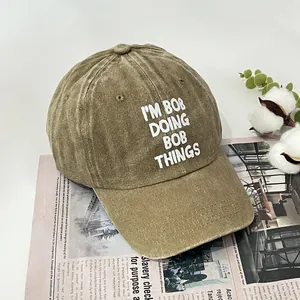 Retro washed cotton baseball cap featuring I'M BOB print on a vintage newspaper background