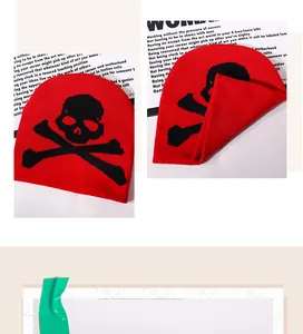 Close-up of red knitted beanie featuring a black gothic skull and crossbones pattern