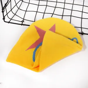 Detailed knit texture of a yellow winter beanie with red star and blue arc patterns