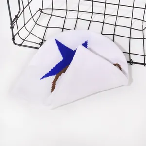 Detail of white knit beanie featuring blue star pattern and brown stripe texture
