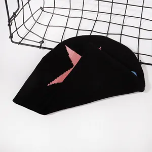 Detail of black knitted beanie featuring pink star embroidery and premium yarn texture