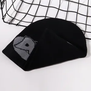 Detail of black knitted beanie showing gray abstract jacquard pattern and soft texture