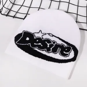 Detail shot of white knit beanie with black Desire lettering on a modern mesh backdrop
