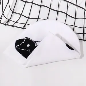 Detail of white ribbed knit beanie with black superhero eye pattern for winter warmth