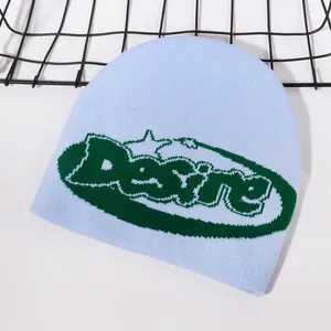Detail of light blue jacquard knit beanie featuring green Desire lettering design