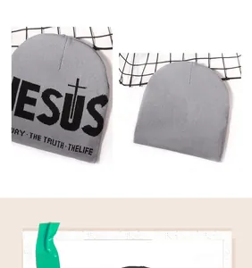 Dettaglio del berretto in maglia grigia con scritta Jesus jacquard e design a croce su rete