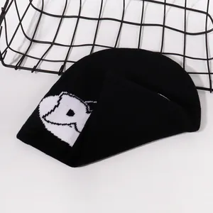 Detail of black knitted beanie featuring white sheep jacquard and fine ribbed texture