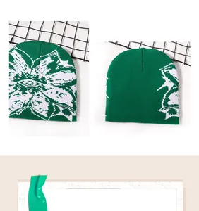 Detail view of green jacquard knit beanie with eye and flower pattern on a mesh rack