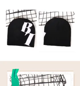 Détail du bonnet en maille noire épaisse avec motif jacquard de lettres BT blanches stylées
