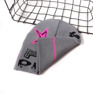 Gray knitted beanie with bright pink star patterns and black letter graphics for winter warmth