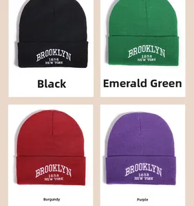 Close-up of winter knit beanies in black, emerald green, wine red, and purple with embroidery