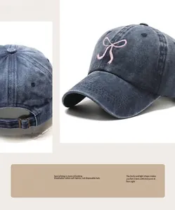 Detail of pink bow embroidery on dark blue washed denim baseball cap with adjustable strap