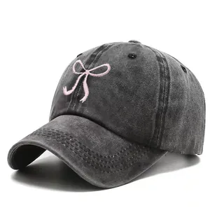 Washed denim baseball cap with pink bow embroidery and a curved brim for sun protection
