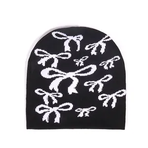 Bonnet en tricot noir tendance avec motifs de nœuds blancs sur fond blanc épuré