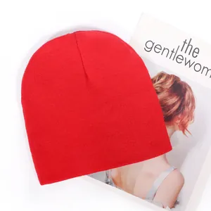 Bright red solid acrylic knit beanie hat for winter outdoor warmth on a white surface